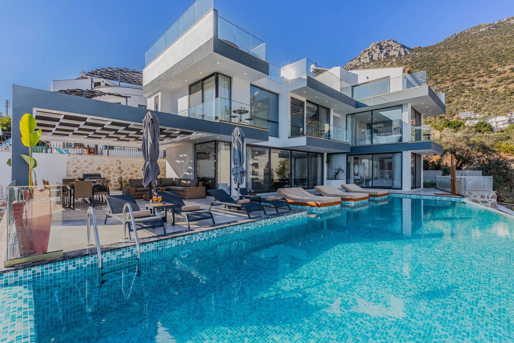 Contemporary villa featuring a spacious infinity pool and breathtaking mountain backdrop. Reference photograph for The Avara Villa.