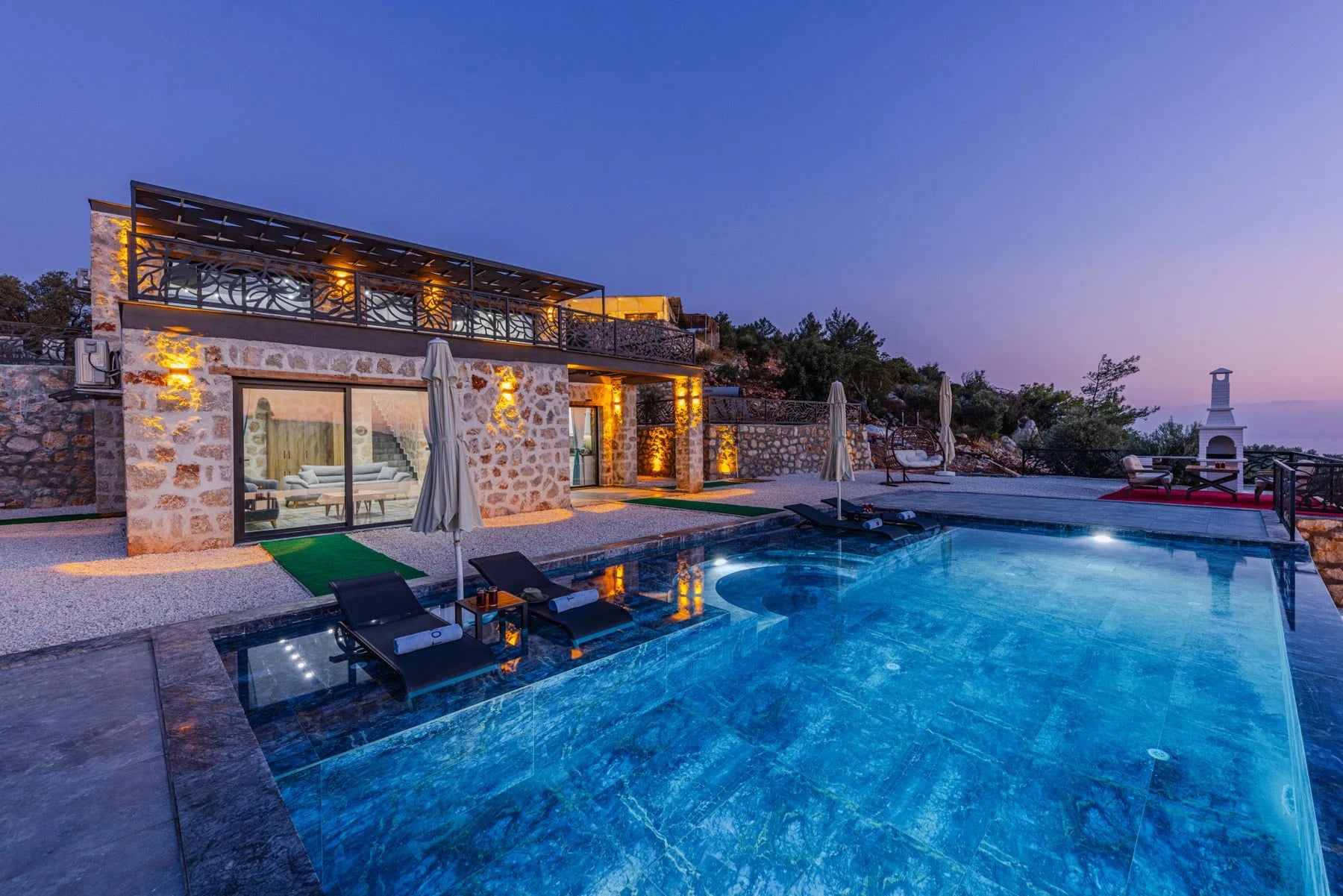 Stone villa with infinity pool offers serene vacation vibes at twilight. Reference photograph for The Avara Villa.