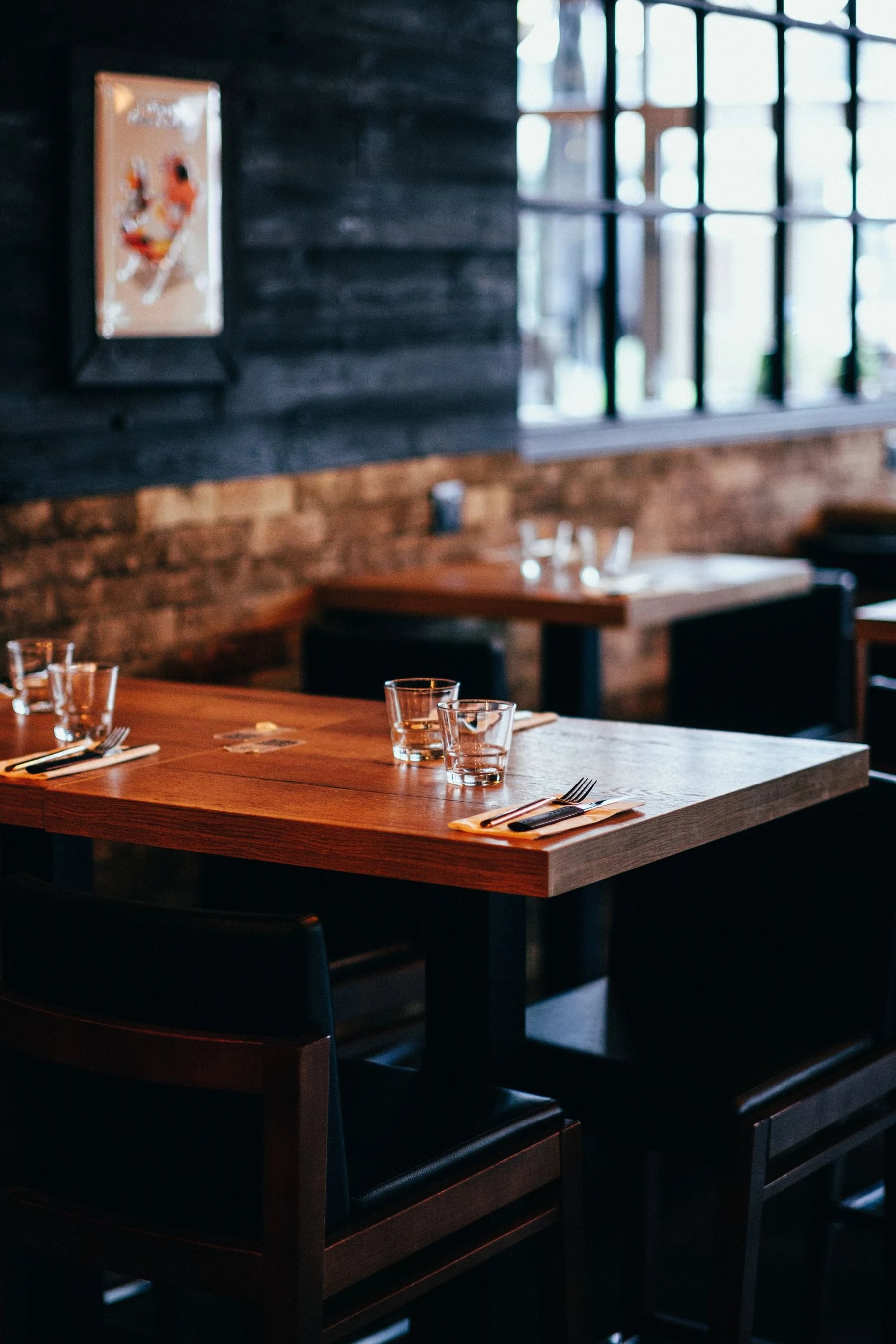 Warm and inviting restaurant interior with wooden tables and elegant glassware, perfect for dining. Reference photograph for Forme Workspace.
