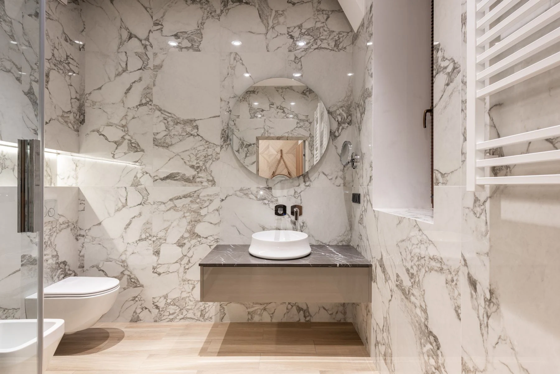 Bathroom with marble walls, modern fixtures, and stylish decor. Reference photograph for Sela Residence.