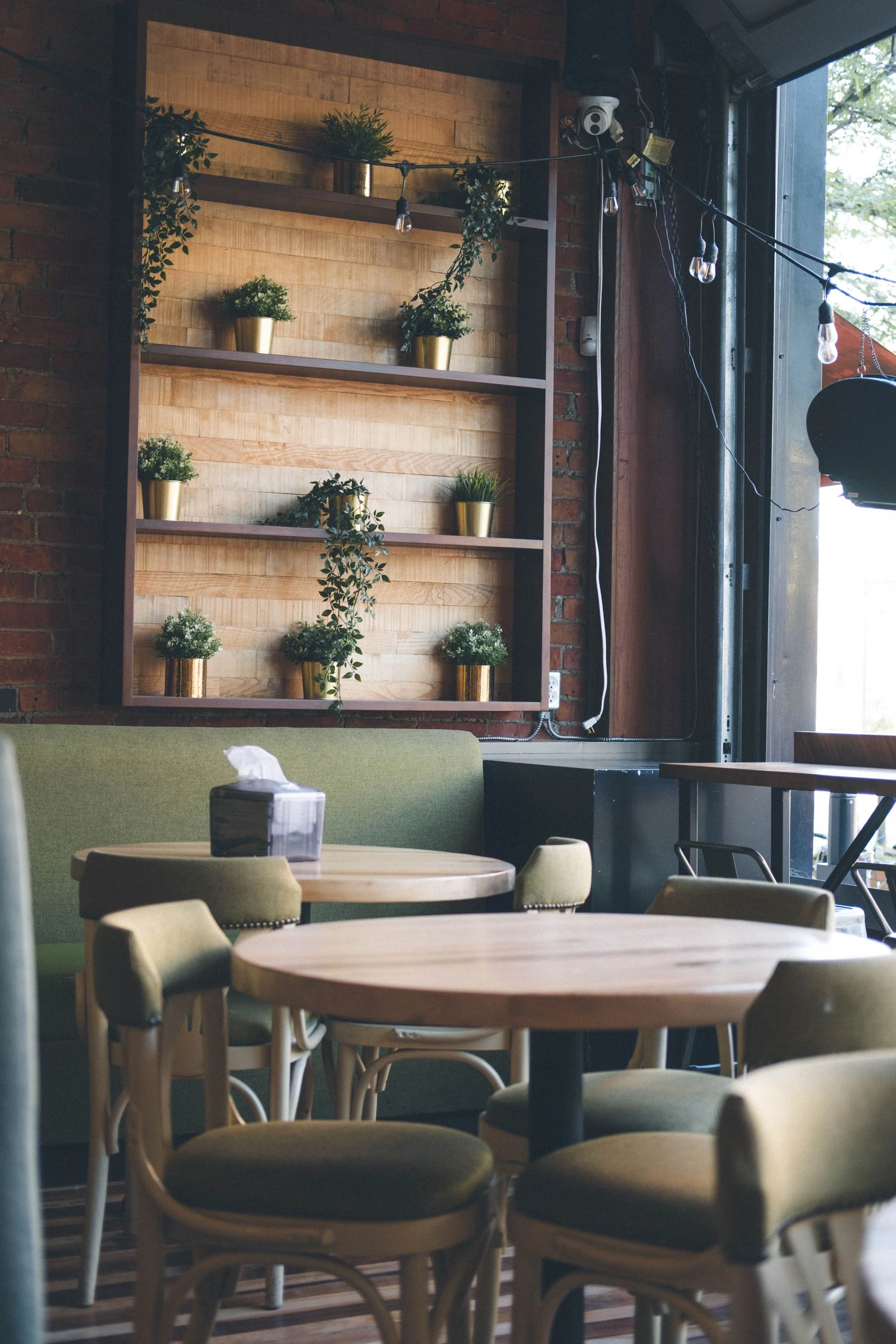 Inviting cafe scene with wooden tables, chairs, and wall-mounted potted plants. Reference photograph for Forme Workspace.