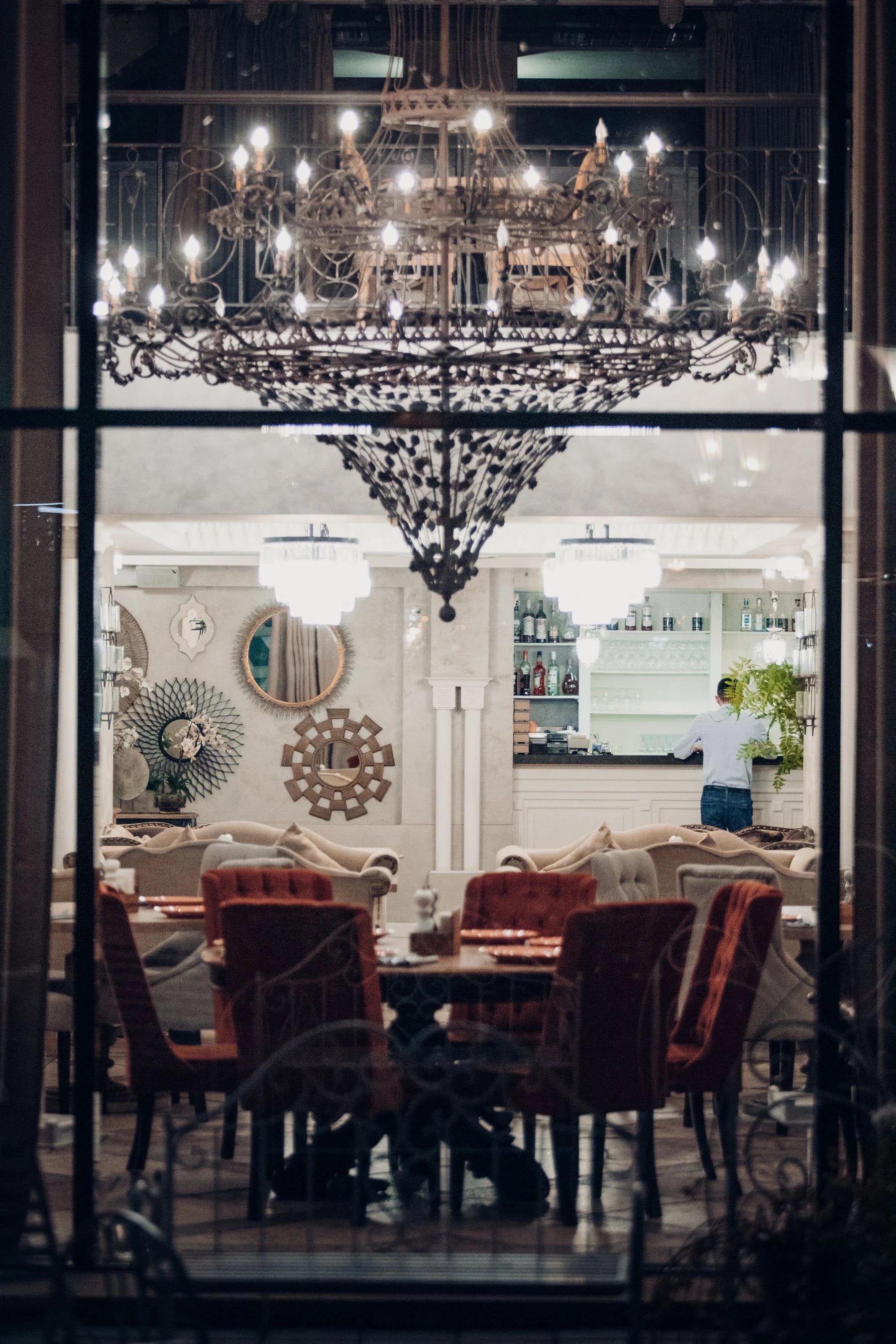 Restaurant interior view with chandelier and elegant decor through window. Reference photograph for Forme Workspace.