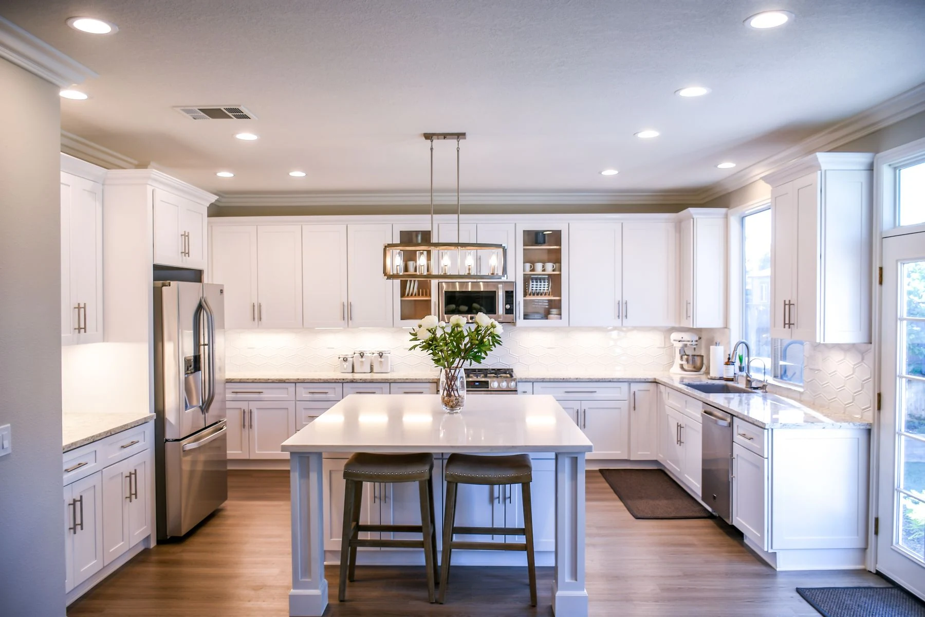 And elegant kitchen featuring white cabinetry, island, and stainless steel appliances. Reference photograph for Atelier Sora.